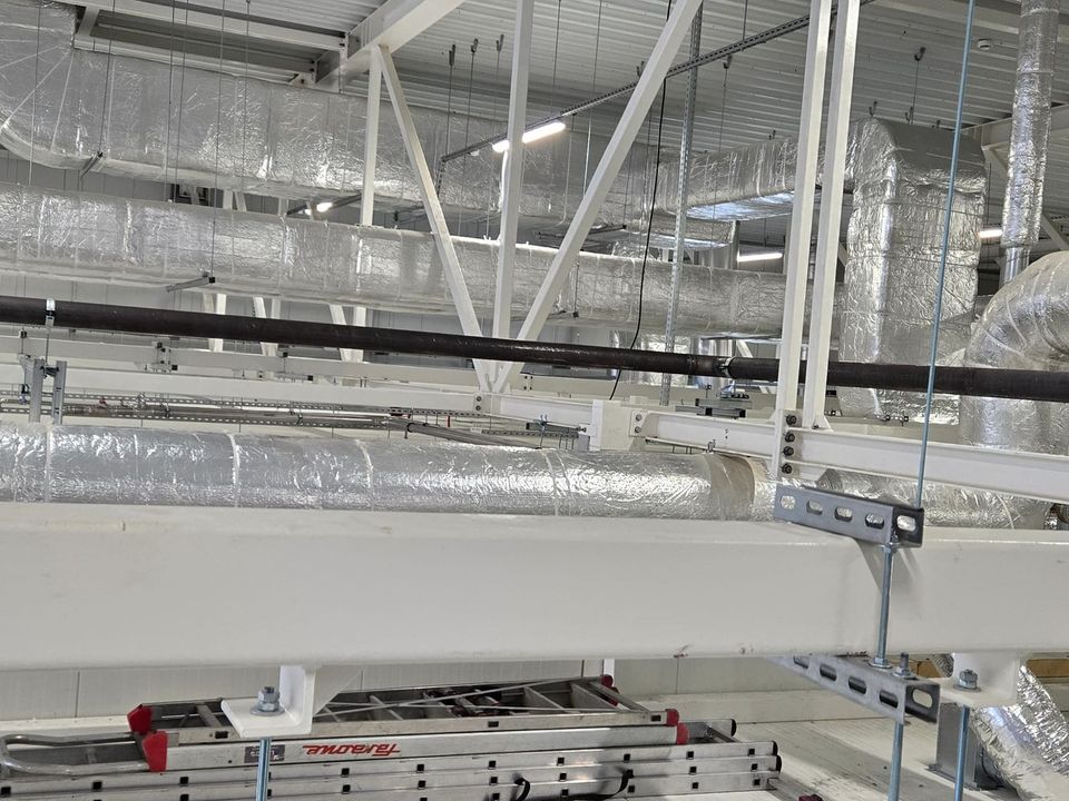 Kanały wentylacyjne w izolacji z folią aluminiową i stalowy rurociąg pod konstrukcją dachu hali